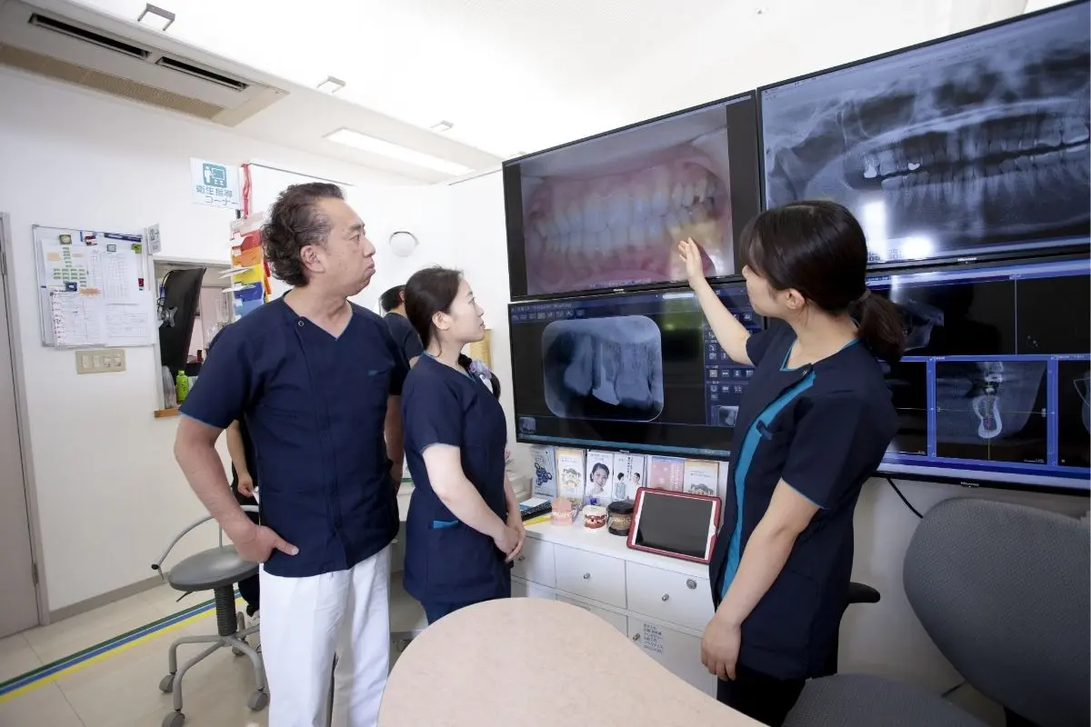 中央歯科クリニックドクター3名がモニターの口腔内写真を見ながら真剣に話し合っている